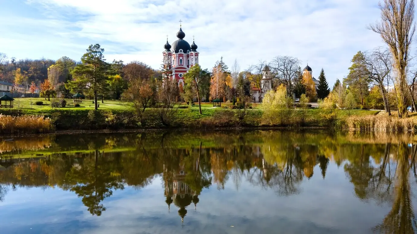 Ansicht des Klosters Curchi mit der Kirche und einem Park; im Vordergrund ein See, in der Republik Moldau.